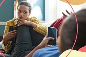 Model holds phone and looks at another person with a suspicious gaze