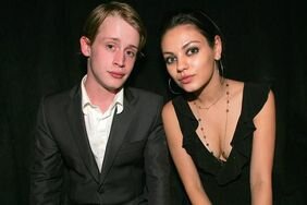 Macaulay Culkin in a suit alongside Mila Kunis in a black top/dress