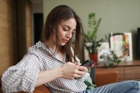 A person with long brown hair, looking at their phone