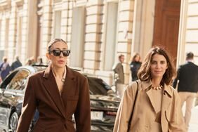 Two people wearing brown clothes walking in the street