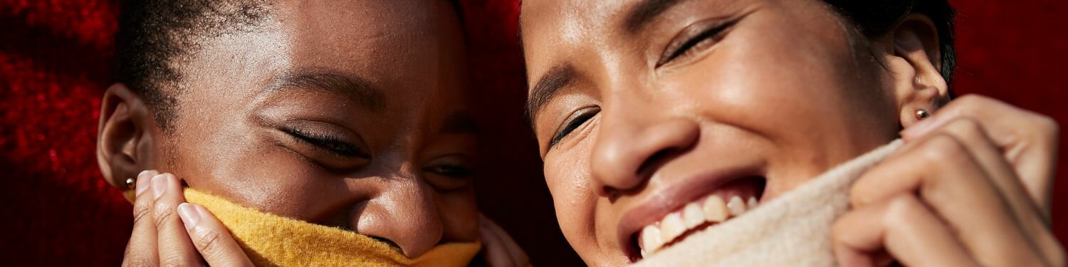 Smiling young female friends wearing turtleneck sweaters against red wall