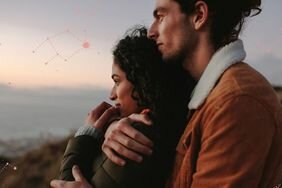 A couple snuggling and overlooking a landscape