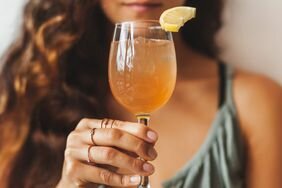 Person holding drink with lemon wedge