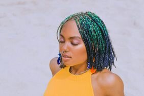 woman with protective hairstyle sitting in sand