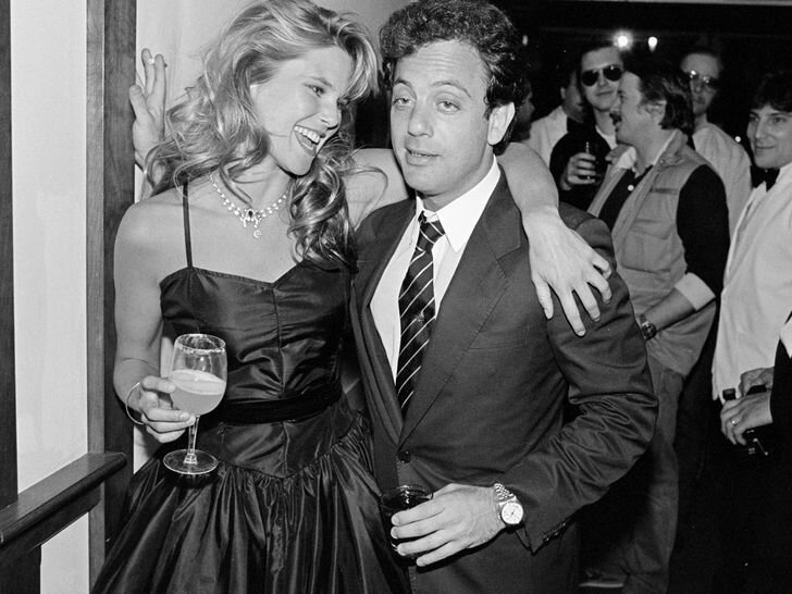 Christie Brinkley and Billy Joel at a party holding drinks