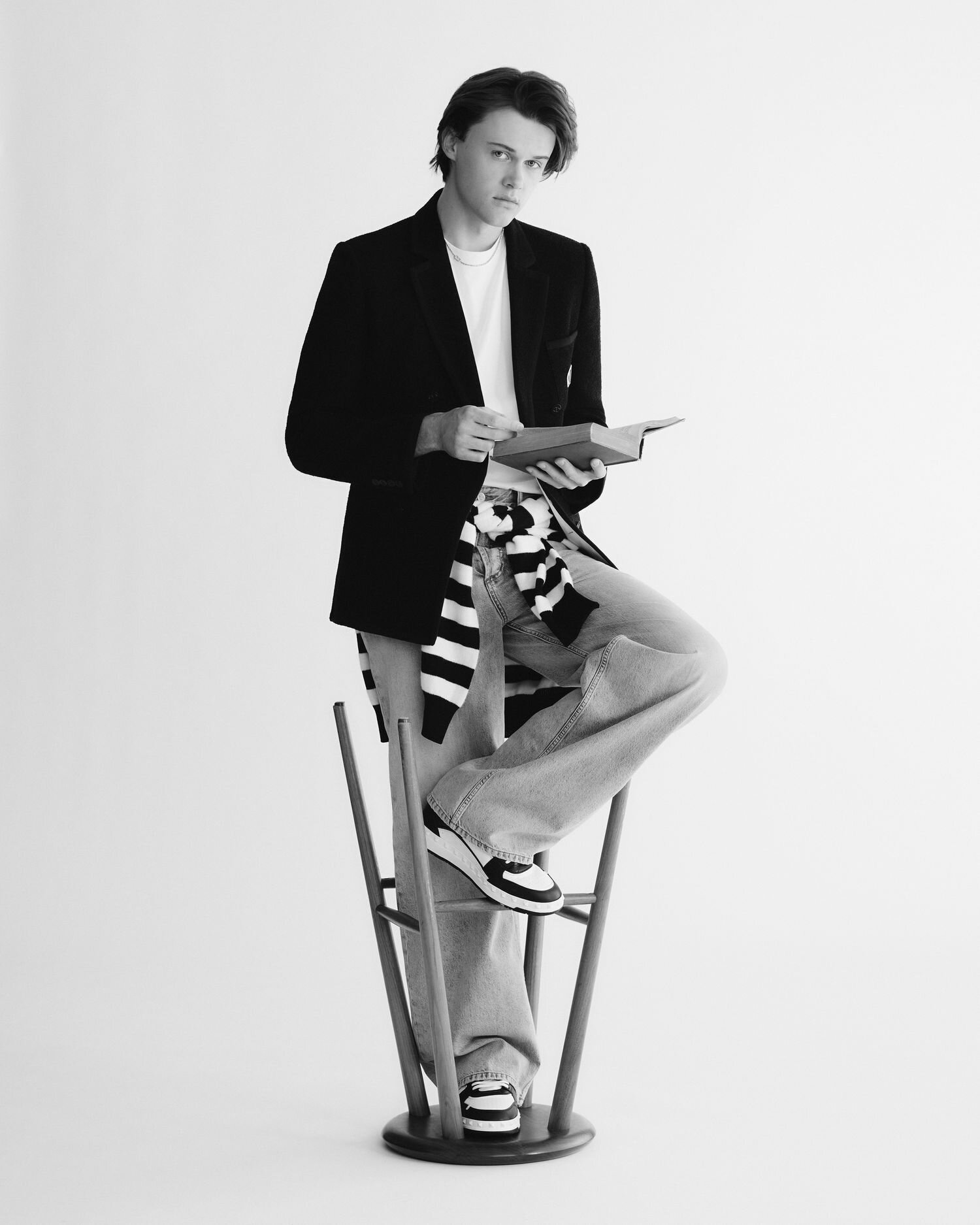 Chris Briney Standing Inside a Stool Reading a Book Wearing a Blazer